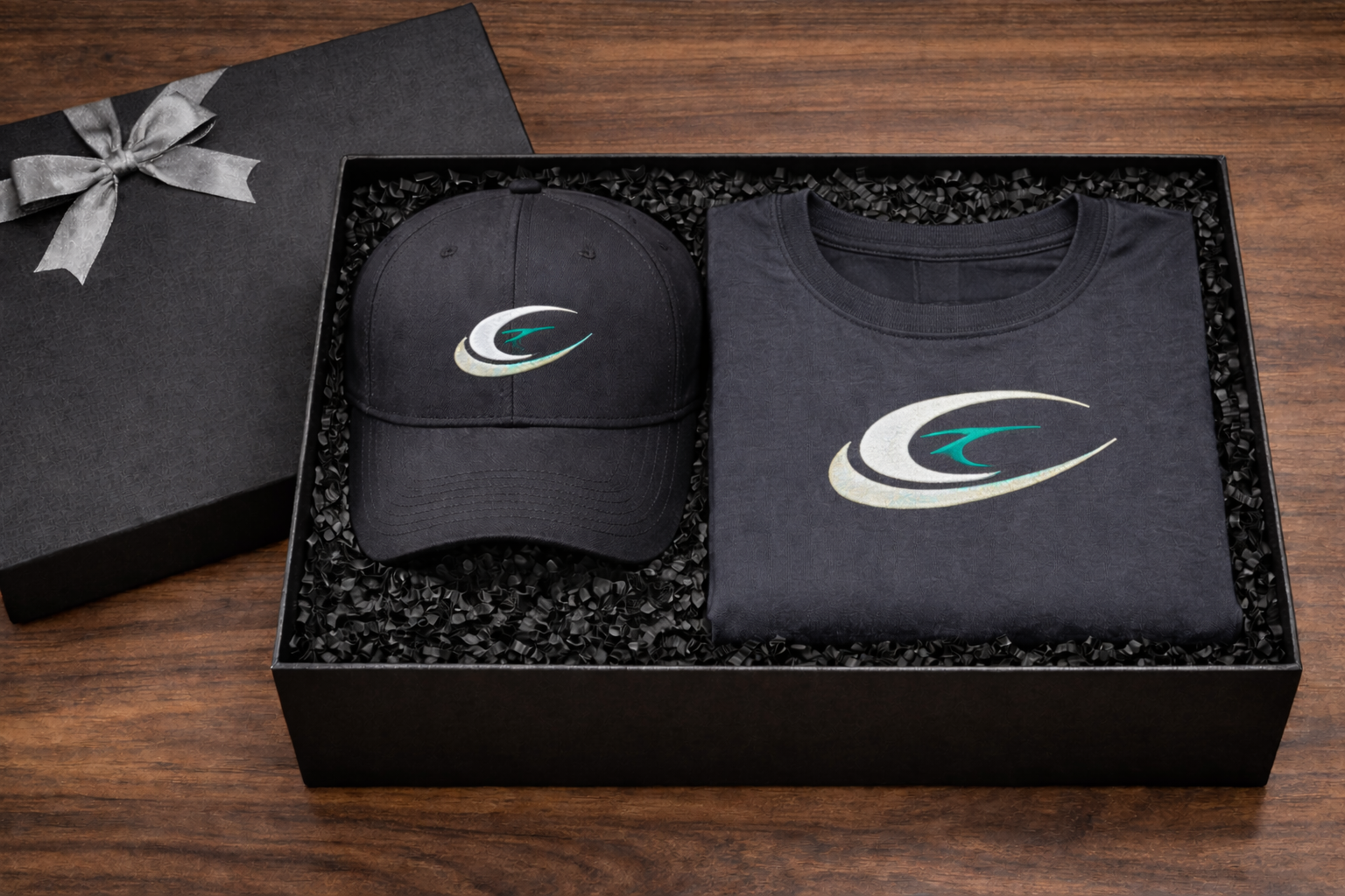 Open black luxury gift box containing embroidered baseball cap and custom logo printed T-shirt arranged in premium packaging.